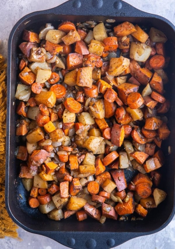 Balsamic Roasted Root Vegetables in a large casserole dish with a golden napkin to the side. Fresh out of the oven, ready to serve