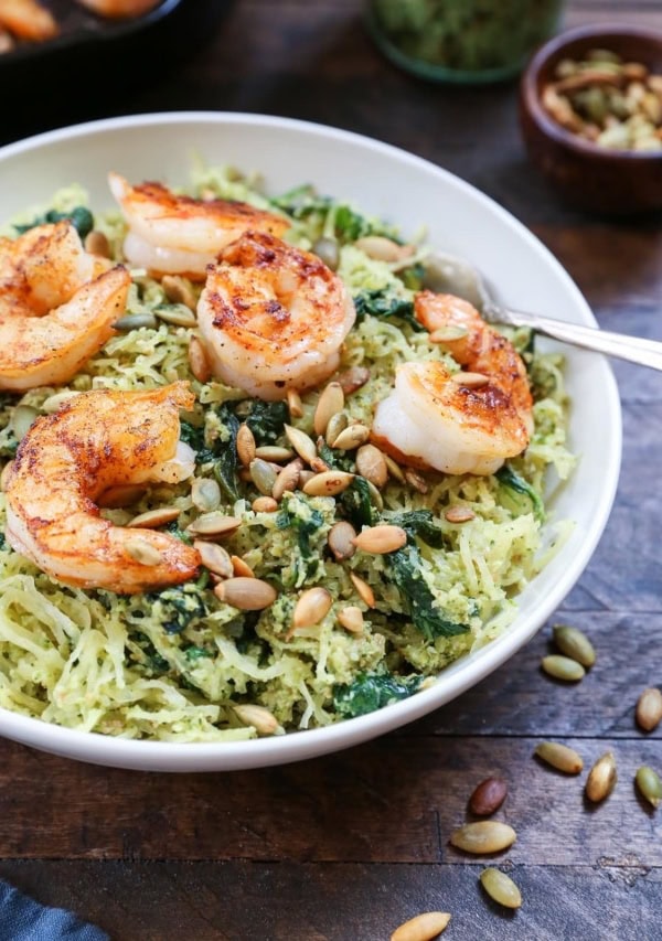 Bowl of pesto spaghetti squash with sautéed shrimp on top.