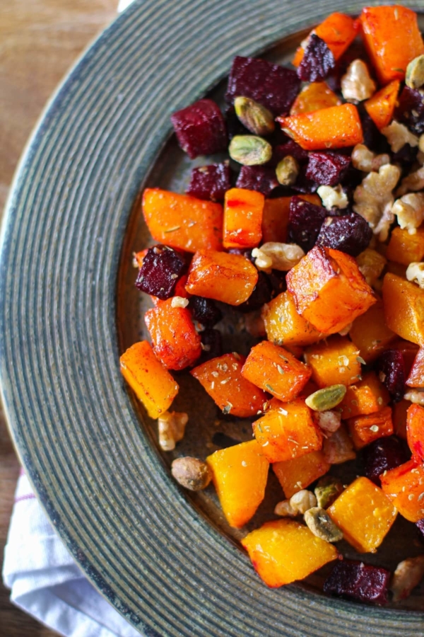 Maple Roasted Butternut Squash and Beets on a rustic wooden plate with a napkin underneath, ready to serve.