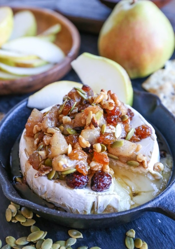 Baked brie in a small cast iron skillet with caramelized pears on top, ready to serve.