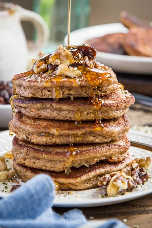 close up stack of paleo carrot cake pancakes with honey being drizzled on top