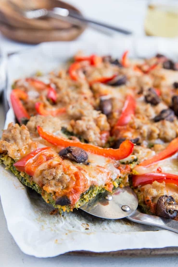 Keto Pizza with Kale Pizza Crust, sausage, sun-dried tomatoes, garlic, and peppers. Low-carb, and grain-free