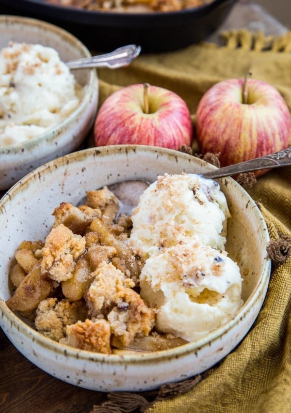 Two bowls of hot apple crisp with scoops of vanilla ice cream