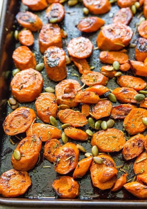 roasted carrots on a baking sheet with pumpkin seeds