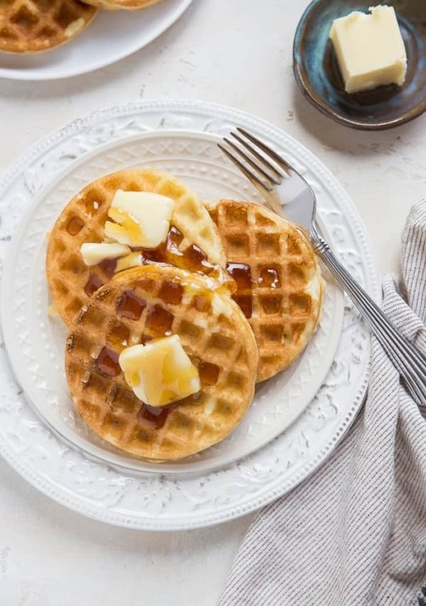 top down photo of two plates of sourdough waffles with butter and honey