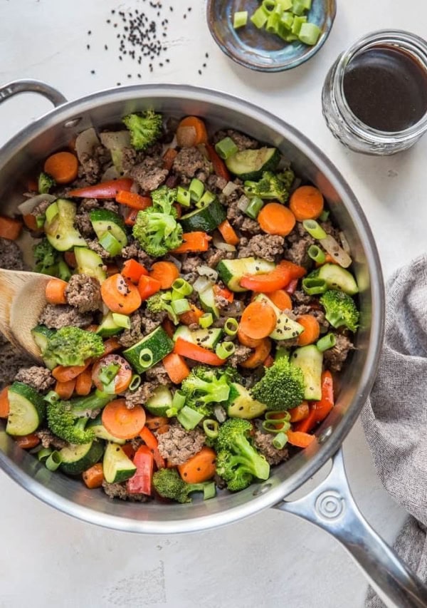 30-Minute Teriyaki Beef Skillet with Vegetables - a skillet, a napkin, a jar of teriyaki sauce and a bowl of chopped green onion