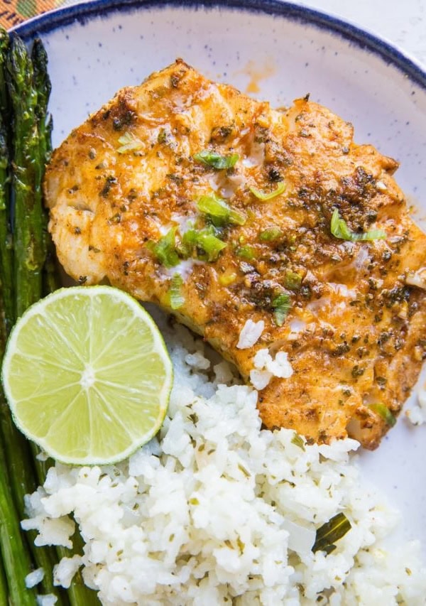 Plate of baked cod with asparagus and cauliflower rice. Ready to eat for dinner!