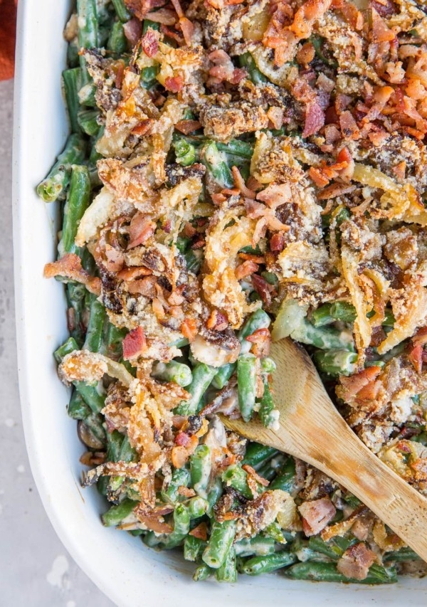 Top down image of a large casserole dish filled with healthy green bean casserole with caramelized onions and bacon on top.