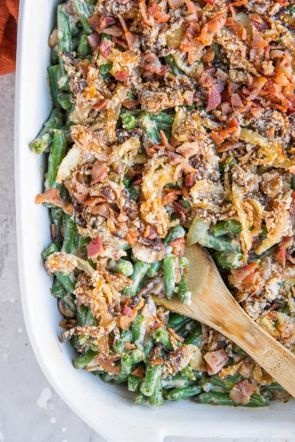 Top down image of a large casserole dish filled with healthy green bean casserole with caramelized onions and bacon on top.