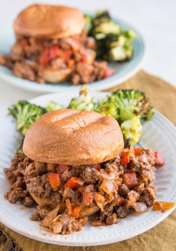 Two plates of sloppy joes with a side of roasted broccoli