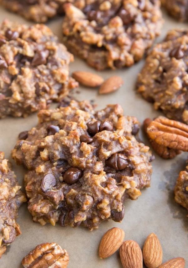 Baking sheet with nutty banana cookies with raw almonds and pecans next to the cookies