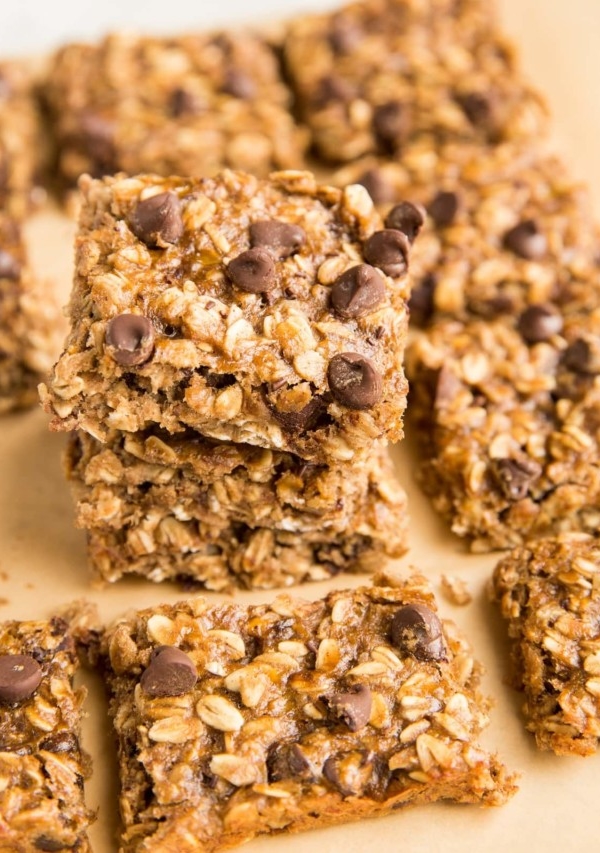 Stack of oatmeal bars sitting on parchment paper with oatmeal bars to the side