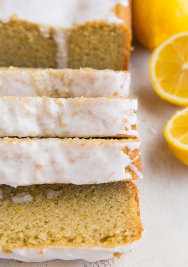 Keto Lemon Pound Cake in slices on a white surface with lemon halves next to it