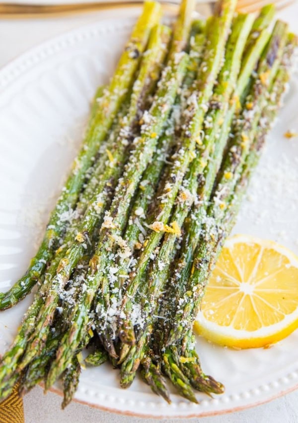 Plate of roasted asparagus sprinkled with lemon zest and parmesan