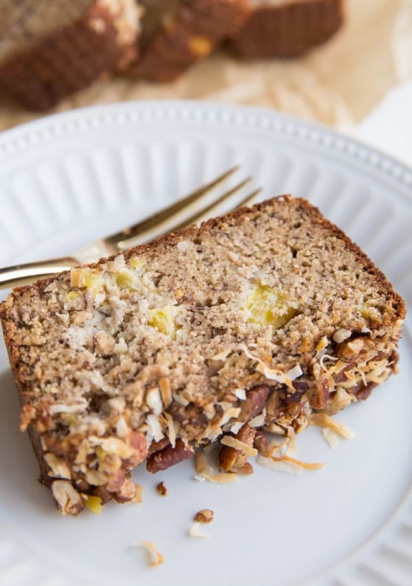 Slice of Grain-Free Hummingbird Bread on a plate with a loaf of bread in the background