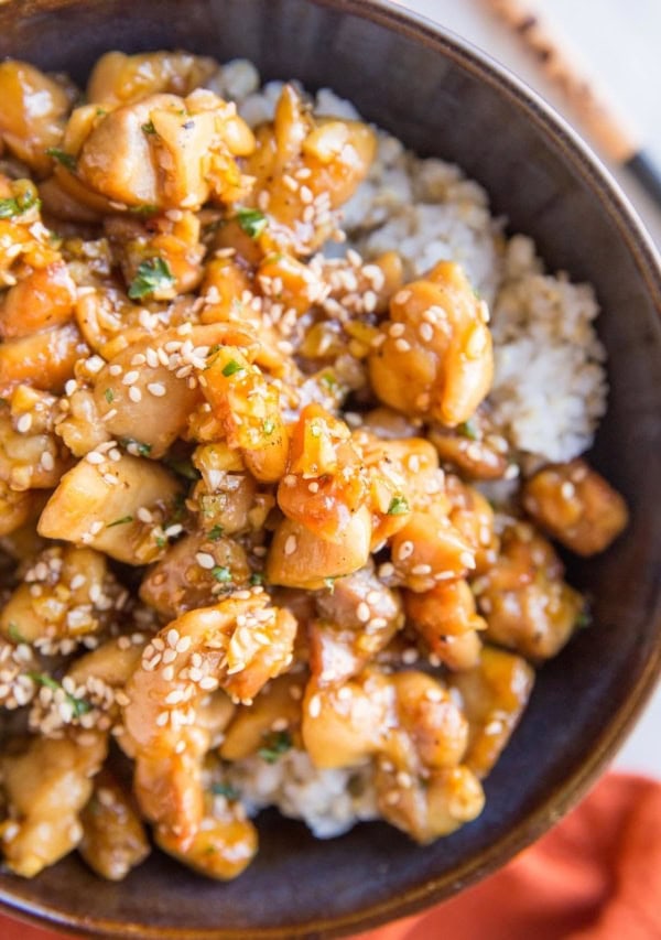 Close up top down image of honey garlic chicken on a bed of rice with a red napkin