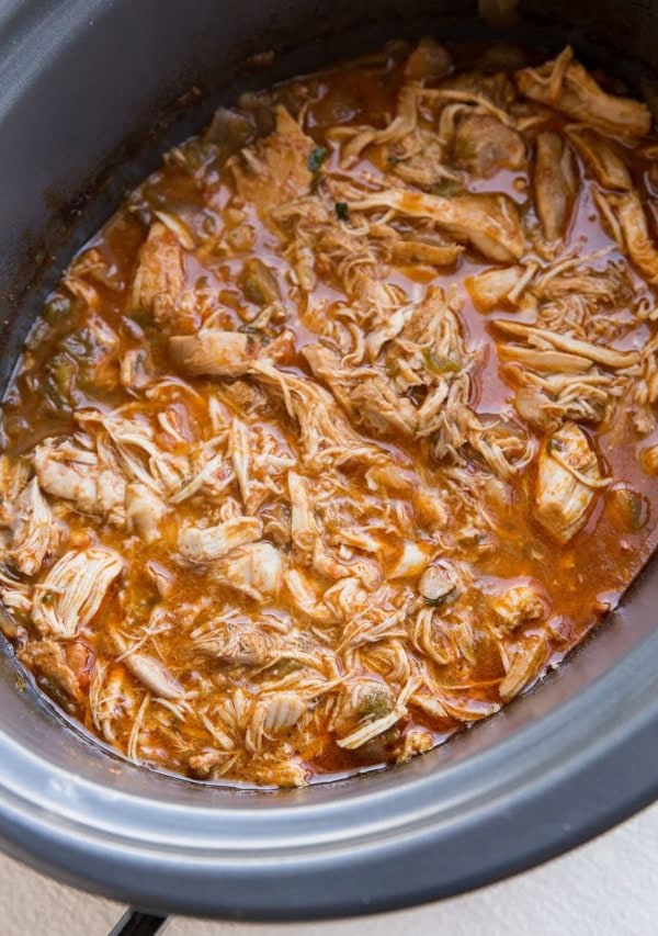 Crock pot full of shredded Mexican chicken for tacos, burritos, enchiladas, and more.