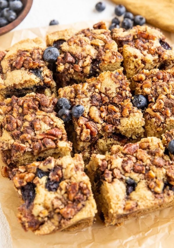 Slices of gluten-free coffee cake on a piece of parchment paper with blueberries to the side.