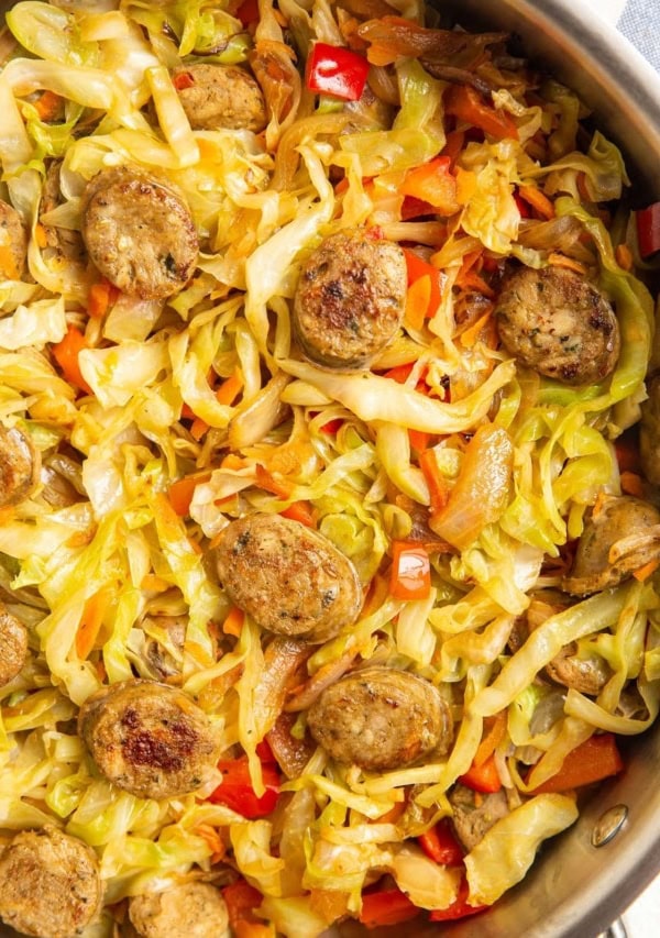 cabbage and fresh vegetables with sausage in a skillet.