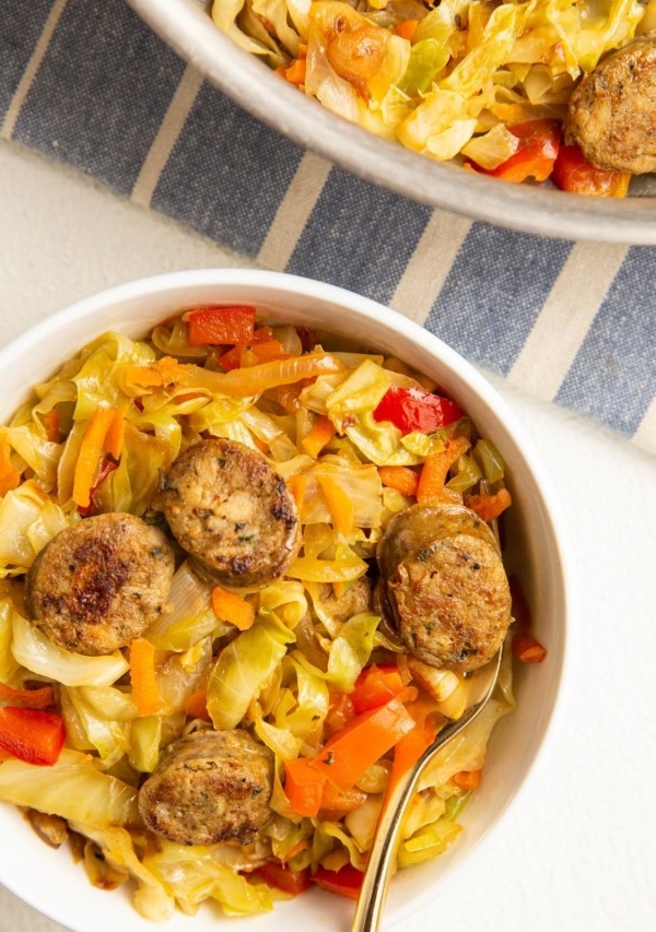 bowl of sausage and cabbage with a skillet of sausage and cabbage