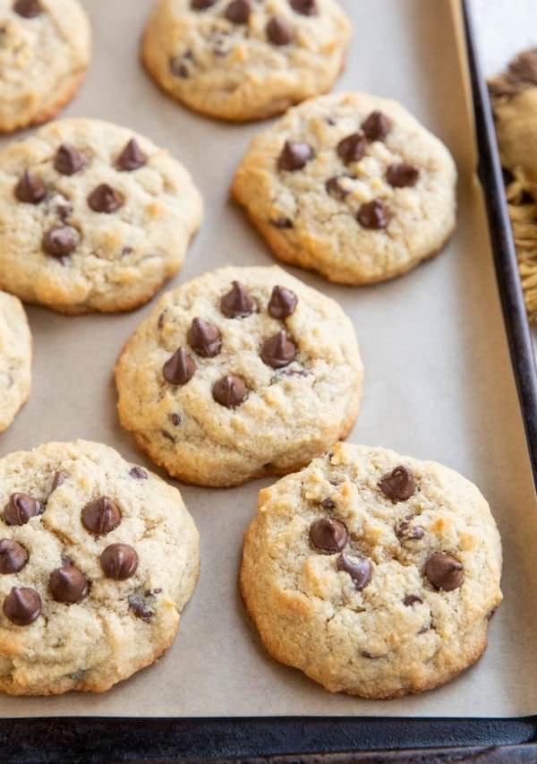 Coconut flour chocolate chip cookies on parchment paper on a baking sheet with a napkin to the side