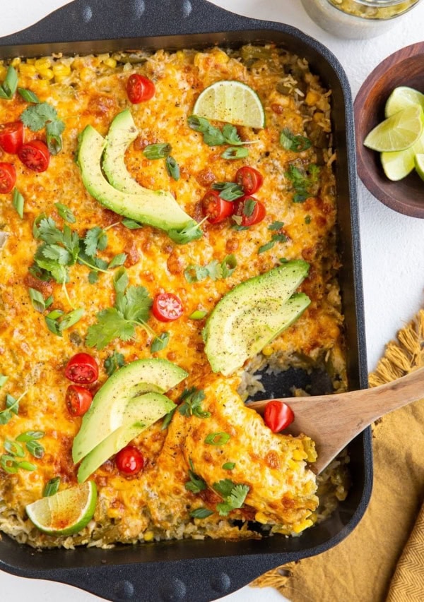 Casserole dish of chicken and rice casserole with a wooden spoon scooping some of it out.