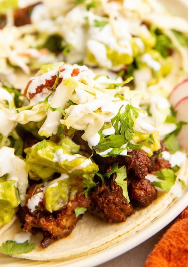 close up image of al pastor tacos on a plate with toppings