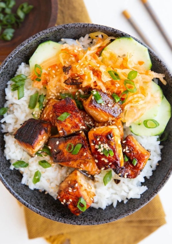 Cooked salmon in a bowl with white rice, sauerkraut and cucumber salad