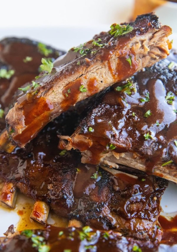 Stack of crock pot ribs on a white serving plate