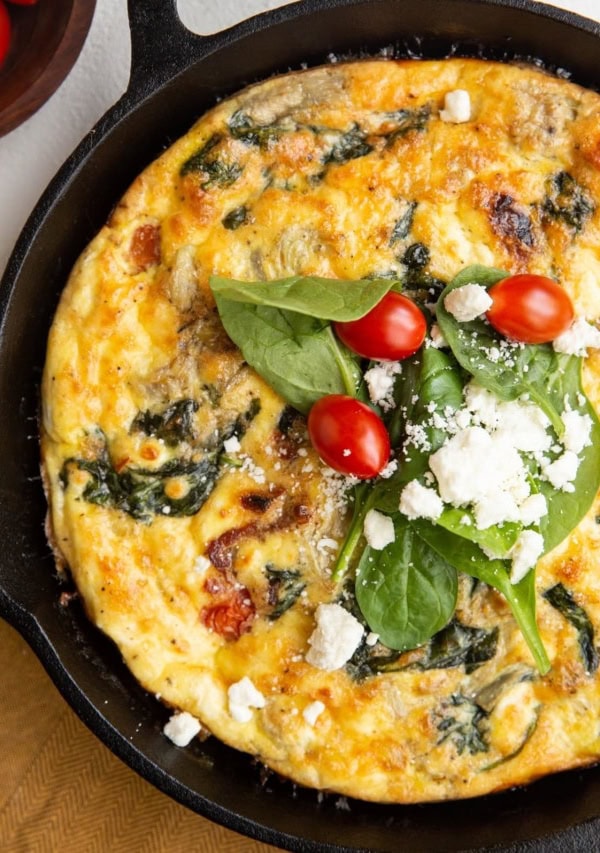 Cast iron skillet with Greek frittata and a golden napkin to the side