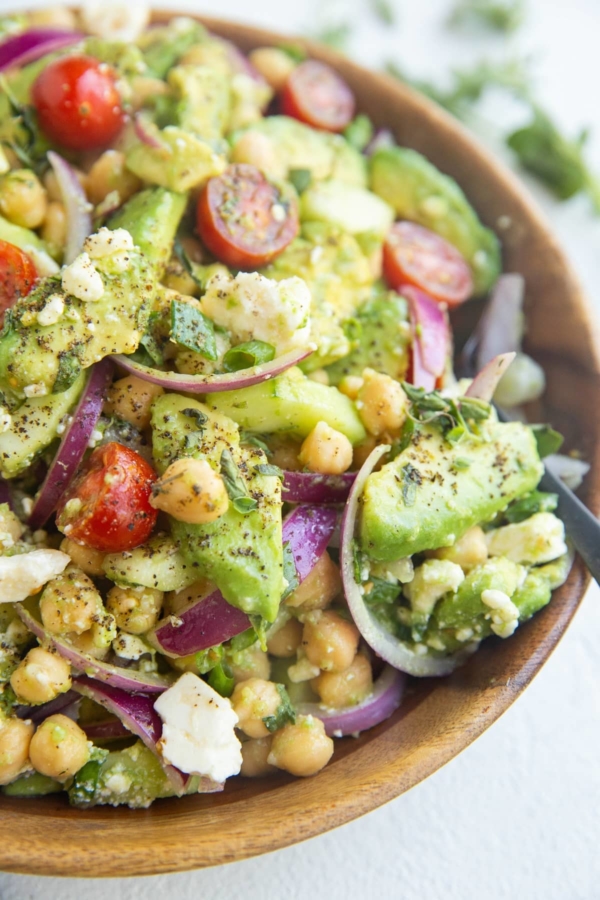 Wooden bowl of avocado chickpea cucumber salad
