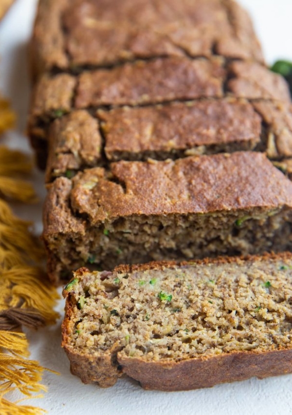 Loaf of zucchini banana bread on a white backdrop in slices.