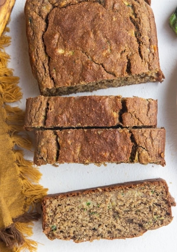 Sliced loaf of zuchini bread with a slice of zucchini bread on a plate