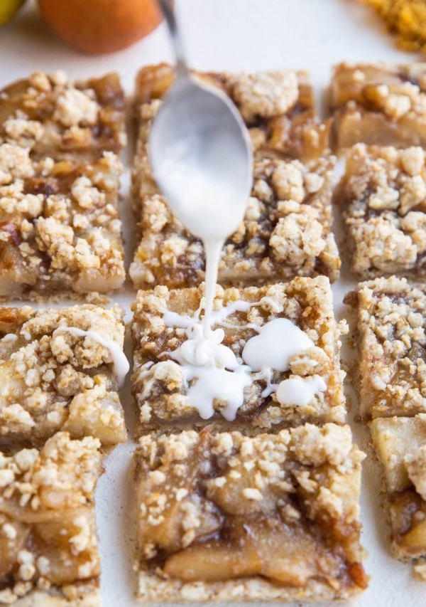 Spoon drizzling glaze over the crumb bars.