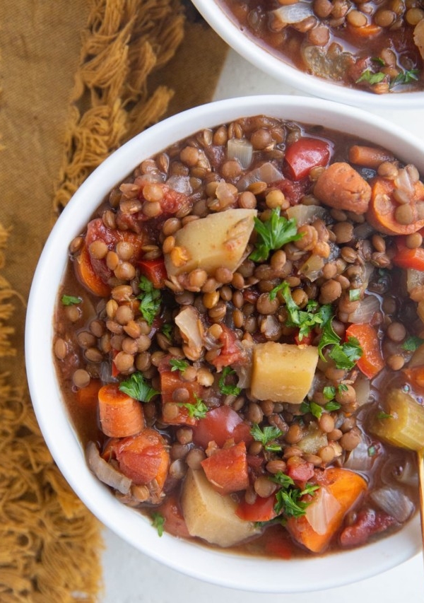 Close up image of two bowls of lentil soup with veggies