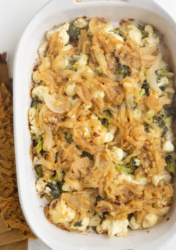 Full casserole dish of broccoli cauliflower casserole with caramelized onions on top.