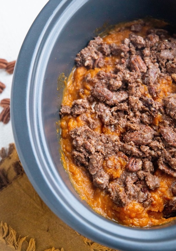 Crock pot filled with sweet potato casserole with delicious pecan topping.