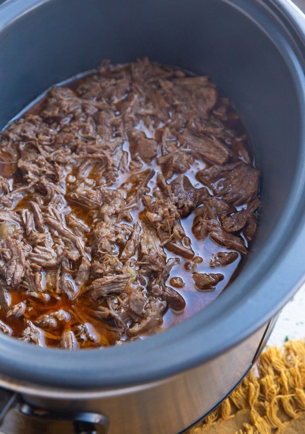 Large crock pot full of shredded beef, ready to be used.