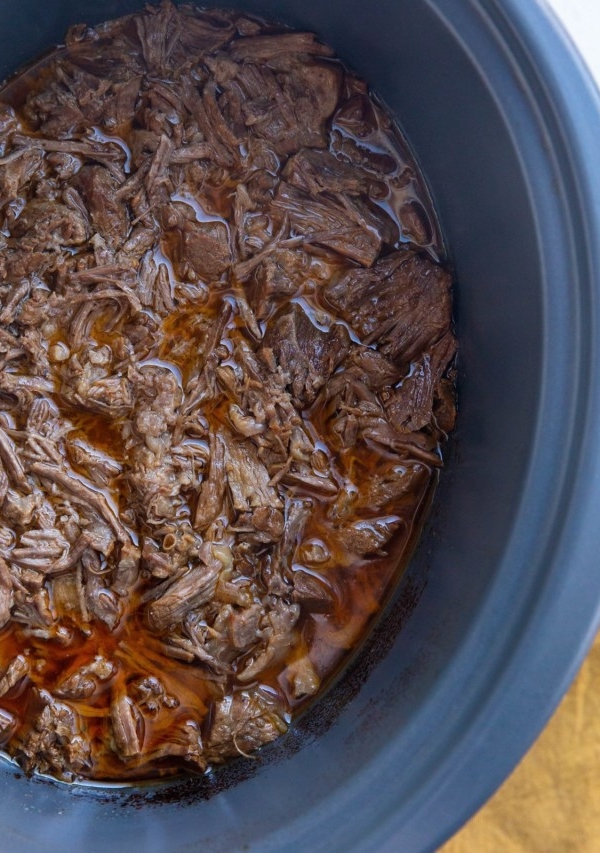 Crock pot full of shredded beef, ready to be used for beef tacos or burritos.