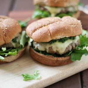 Lamb Burgers with kale and mint pesto on a cutting board, ready to eat.