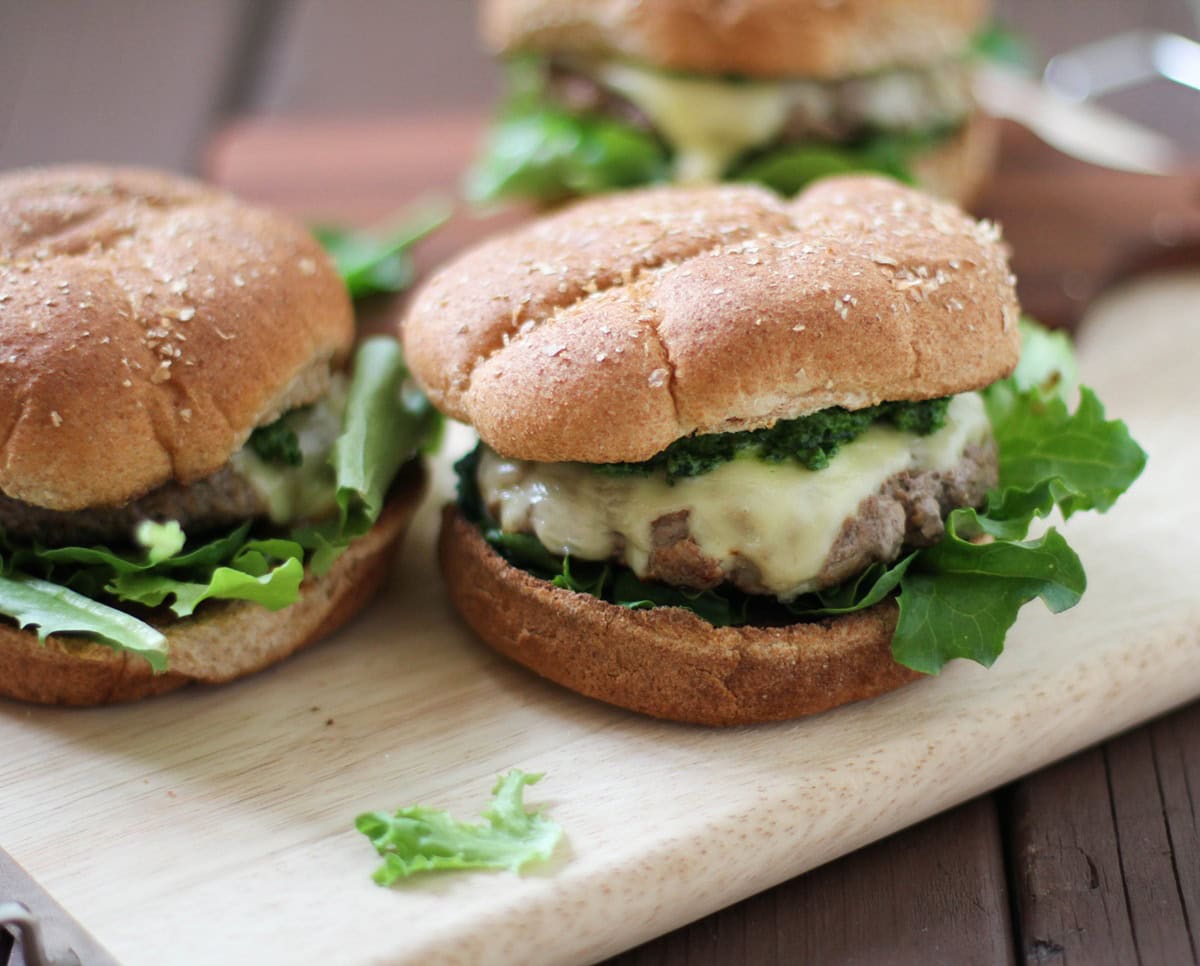 Lamb Burgers with kale and mint pesto on a cutting board, ready to eat.