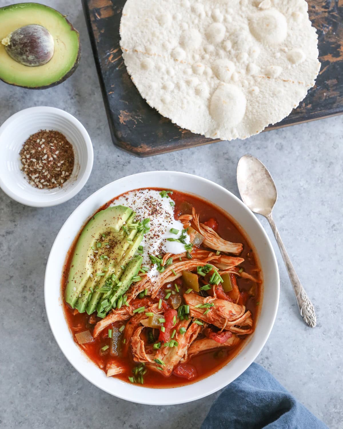 bowl of enchilada soup with tortillas, napkin and spoon