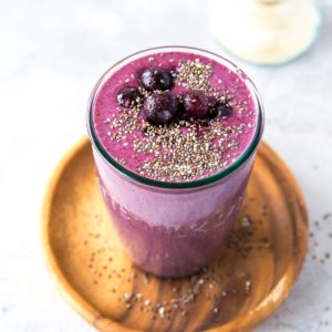 Beautiful purple smoothie in a glass with blueberries and chia seeds on top. Ready to drink.