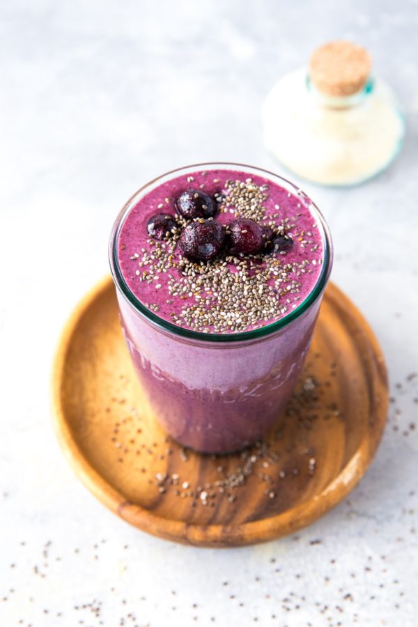 Beautiful purple smoothie in a glass with blueberries and chia seeds on top. Ready to drink.