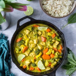 Aip curry in a cast iron skillet with fresh limes to the side.