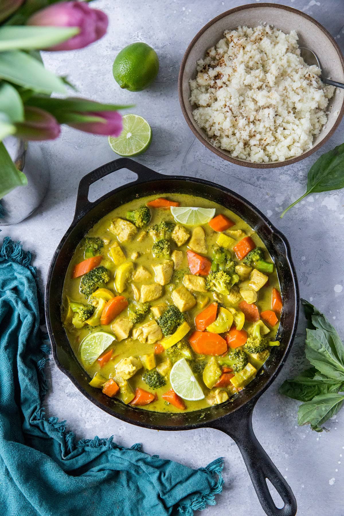 Aip curry in a cast iron skillet with fresh limes to the side.