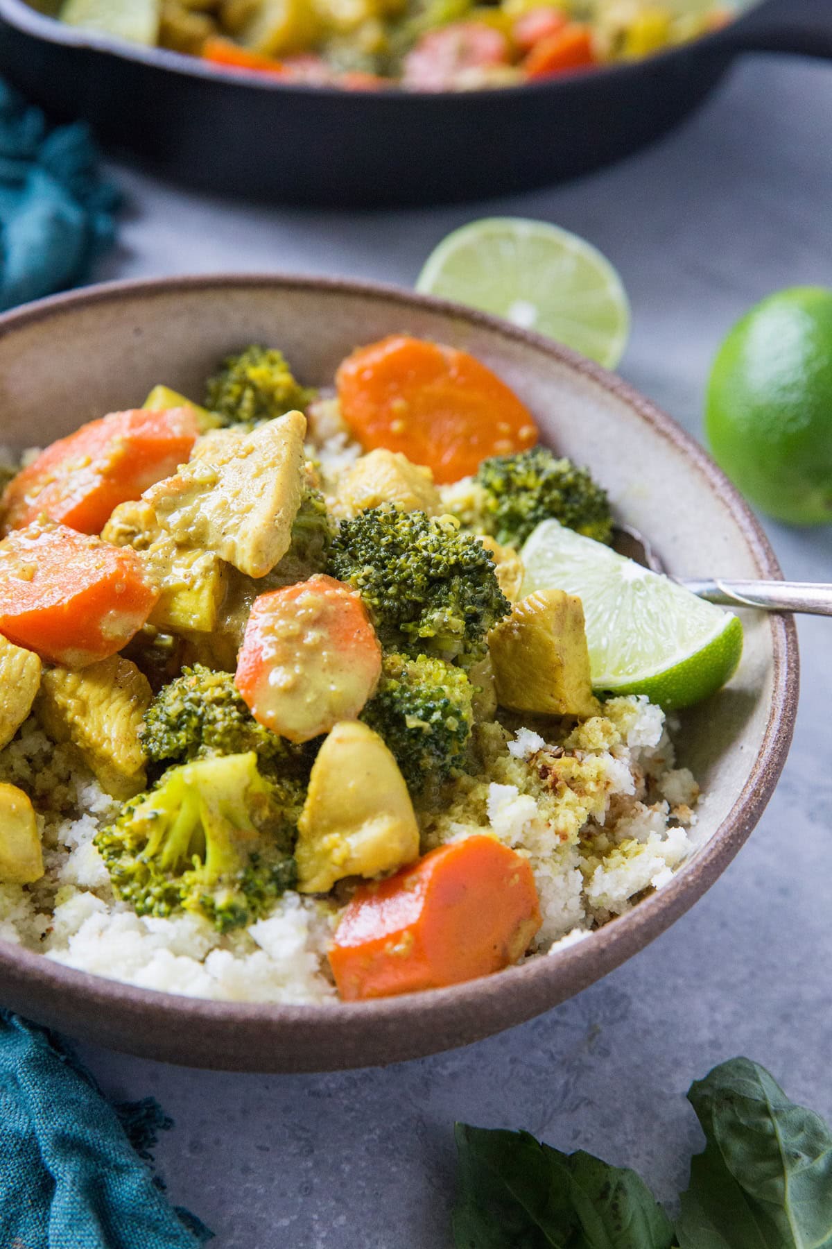 Large bowl full of nightshade-free curry on top of cauliflower rice with the rest of the skillet of curry in the background.