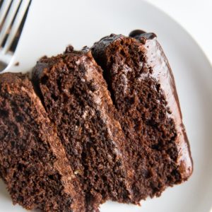 Large slice of almond flour chocolate cake on a white plate with 3 layers.