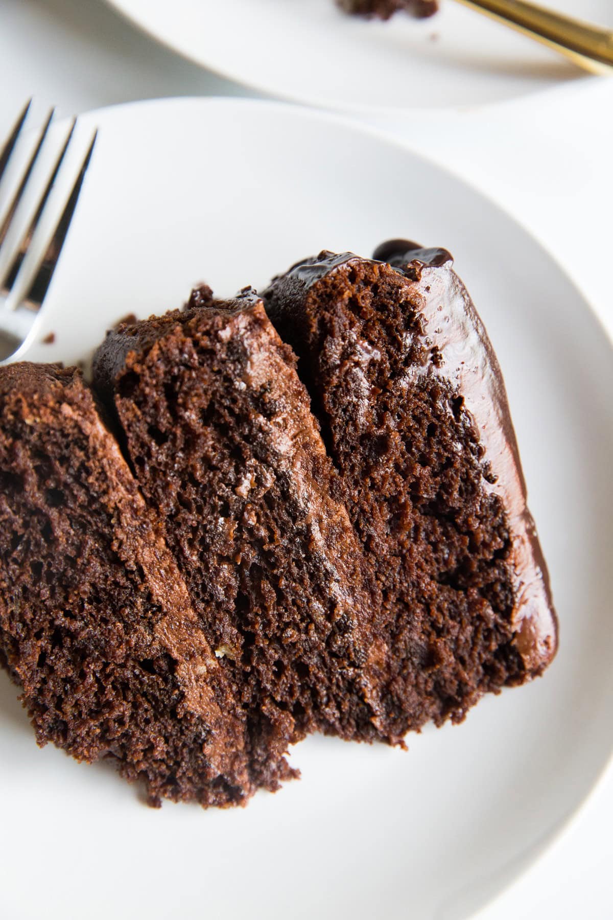 Large slice of almond flour chocolate cake on a white plate with 3 layers.