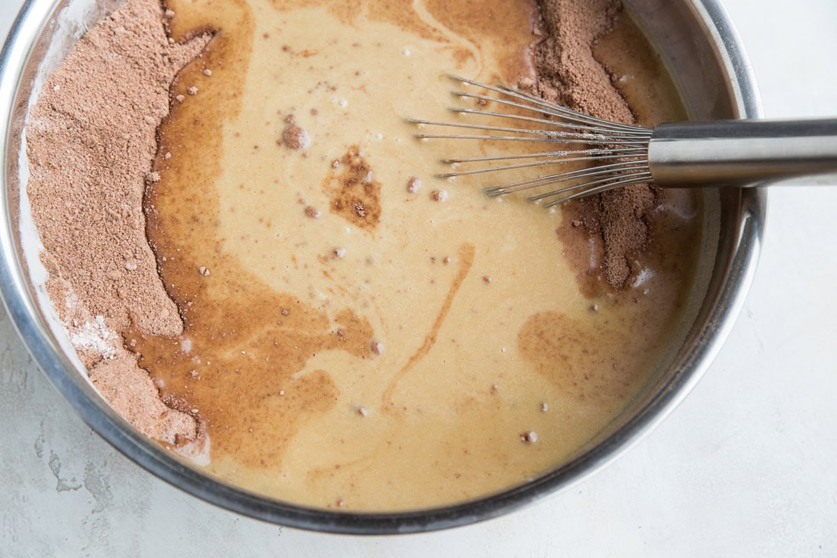 Stainless steel bowl full of dry ingredients and wet ingredients about to be mixed together.